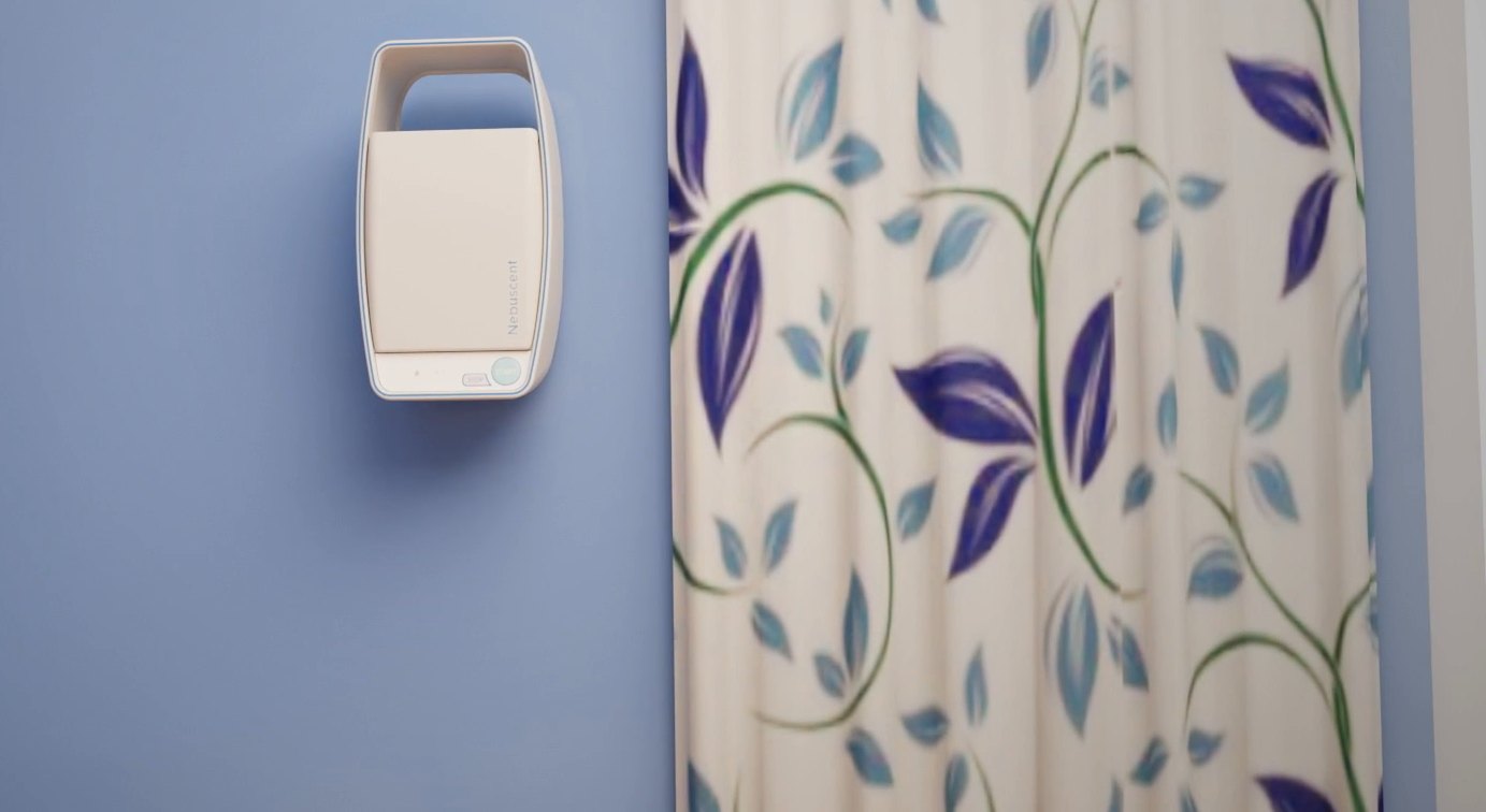 A Nebuscent unit mounted on a blue patient room wall next to a patterned privacy curtain